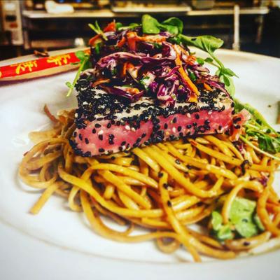 Sesame seared tuna with Asian slaw and ginger sriracha aioli over spicy lo mein.