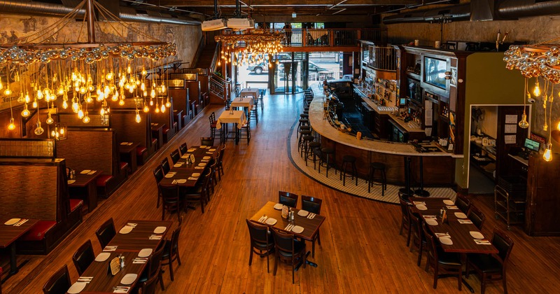 Interior, open space dining area, high and low seating tables, seating booths, bar with stools