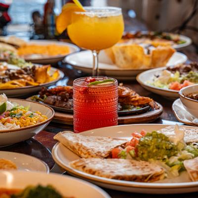 Assorted Mexican dishes and cocktails on a table.