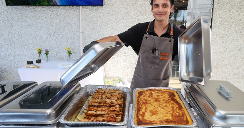 Staff member opening catering chafing dishes filled with food