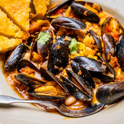Southwest Mussels served with toasted baguette, close up.