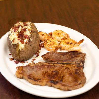 Surf and turf, with grilled steak, shrimp, and loaded baked potato.