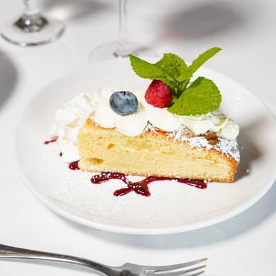 Italian Olive Oil Cake topped with whipped cream, with berries and mint leaves.