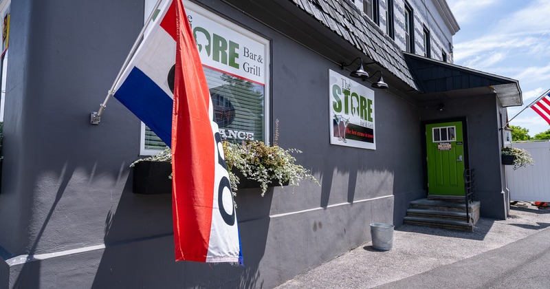 Exterior featuring dark gray siding, a green door, and prominent signage