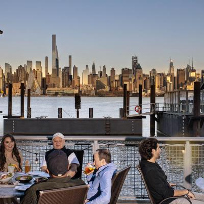 People sitting at tables in front of the city skyline, enjoying the view and each other's company.