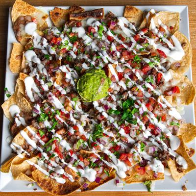 Carne asada nachos with sour cream, pico de gallo, and guacamole.