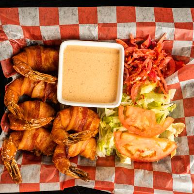 Diablo shrimp wrapped in bacon, served with a dipping sauce and a small salad.