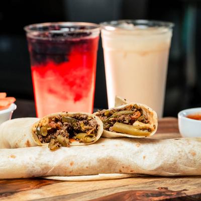 Ground meat burrito served on a table with aguas frescas.