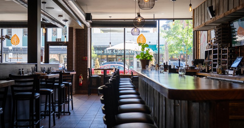 High dining tables for two guests lined up near the bar