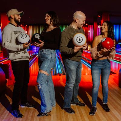 4 people holding bowling balls.