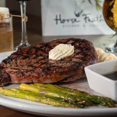 Delmonico steak served with mashed potatoes, au jus, and asparagus.