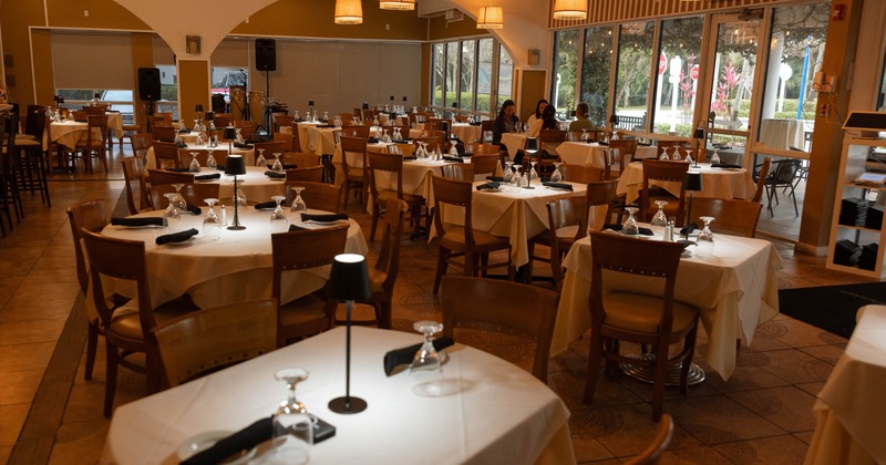 Spacious, elegant restaurant with white tablecloths, wooden chairs, and soft overhead lighting
