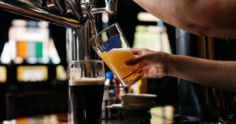 A bartender pouring light beer from a tap into a glass