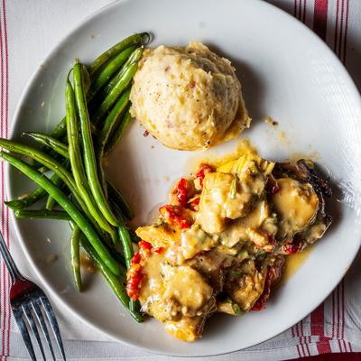 Chicken Caprino dish served with green beas and mashed potatoes.