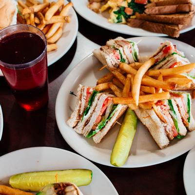 Variety of food and drinks displayed on the table with sandwiches in the middle