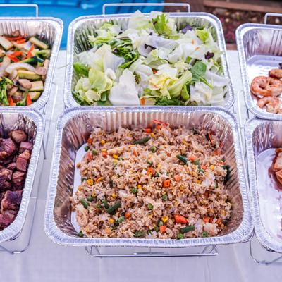 Assorted catered dishes in aluminum trays.