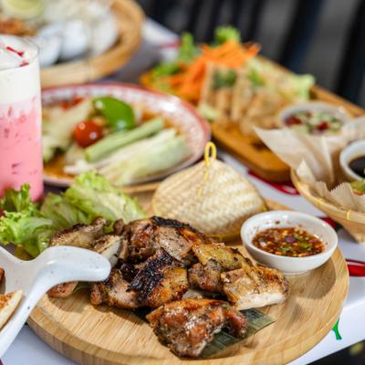 Thai food spread featuring smoky grilled chicken, papaya salad, and sticky rice.