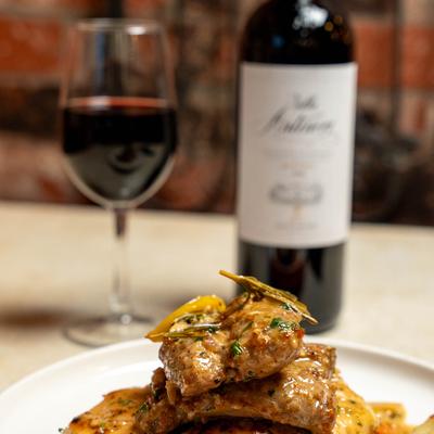 Herb-glazed chicken served with vegetables, paired with a glass of red wine.