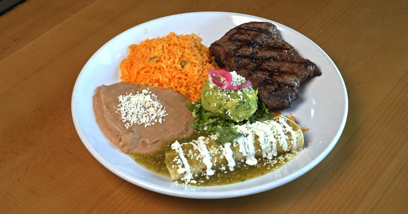 rilled steak served with rice, beans, and enchilada covered in green sauce