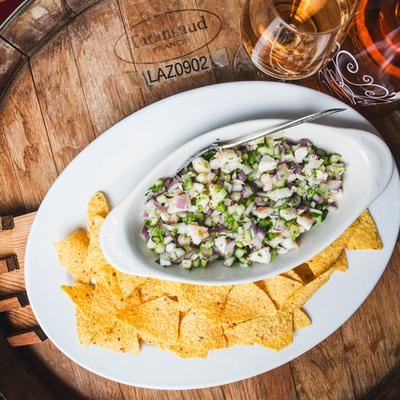 Shrimp Ceviche with chips and wine, served on a wooden barrel, top view.