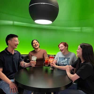 Interior, a group of friends enjoying drinks and conversation at a table.