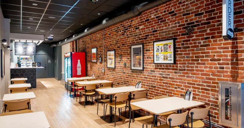Interior of a modern cafe with a brick wall, tables, and a counter