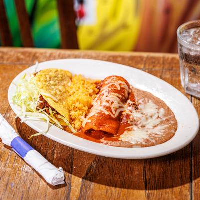 Combination plate featuring a cheese-covered enchilada, a taco, rice, and refried beans.