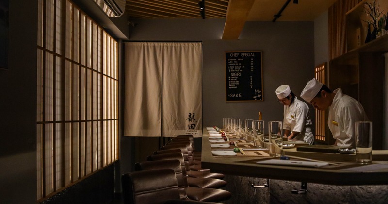 Interior, sushi bar, comfortable leather padded stools, staff working behind the bar