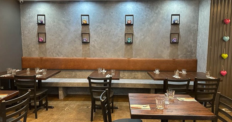 Interior with built-in bench, several tables and chairs and wall decorations