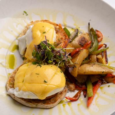 Eggs Benedict served with potatoes and vegetables.
