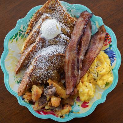 A plate with eggs, toast, patty, bacon, and smash browns.