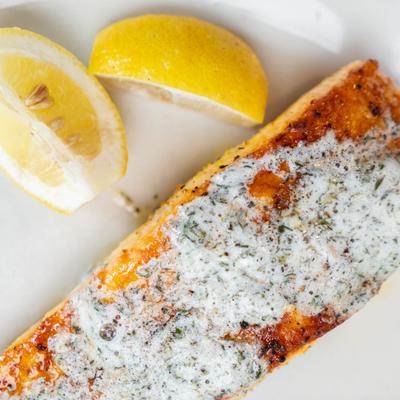 Salmon filet topped with dill butter sauce and served with lemon wedges.