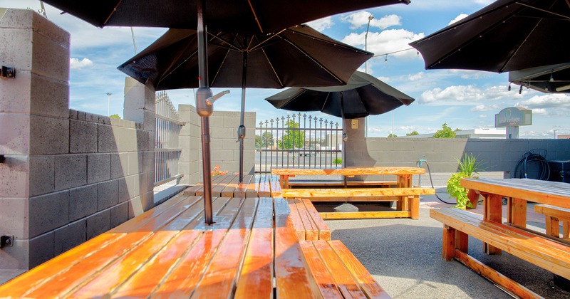 Outdoor seating area, wooden tables, benches, black parasols