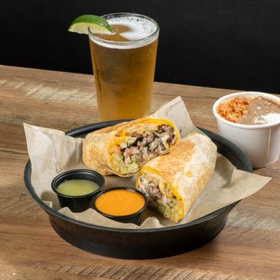 Burrito with meat on plate with salsa, beans, rice and a beer with lime.