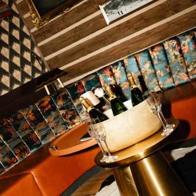 A cozy lounge with champagne bottles in a basket on a wooden table.