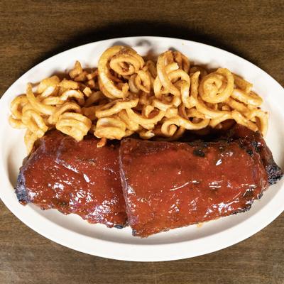 Barbecue ribs served with curly fries, overhead view.