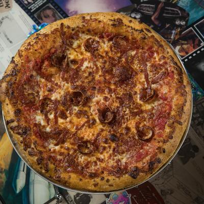 Pepperonius Maximus Pizza served on a metal stand, overhead view.