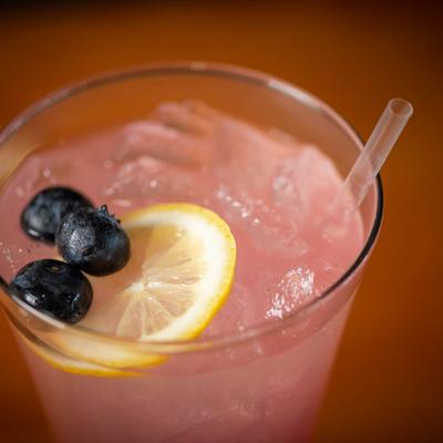 Fruit lemonade, garnished with blueberries and lemon wheel, close up.