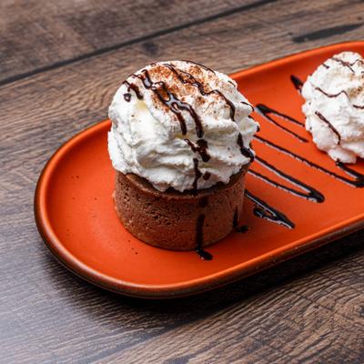 Mini chocolate cheesecake topped with whipped cream and dark chocolate drizzle.