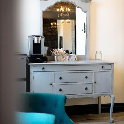 Bridal Suite interior, gray vintage vanity with mirror near a teal armchair.