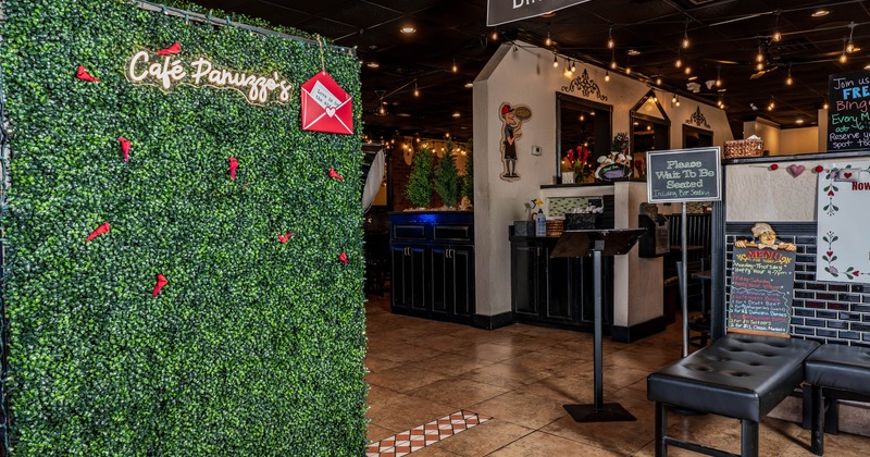 Entrance area with green wall with a neon sign and informational signs for diners