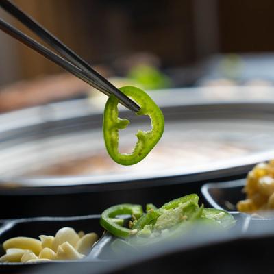 Chopsticks holding a pepper.