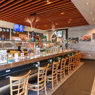Sushi bar with wooden chairs and conveyor belt.