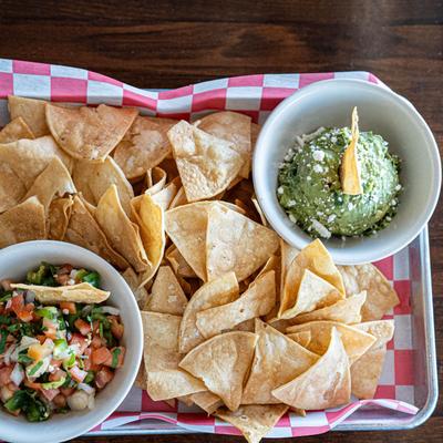 A tray with tortilla chips, guacamole, and pico de gallo.