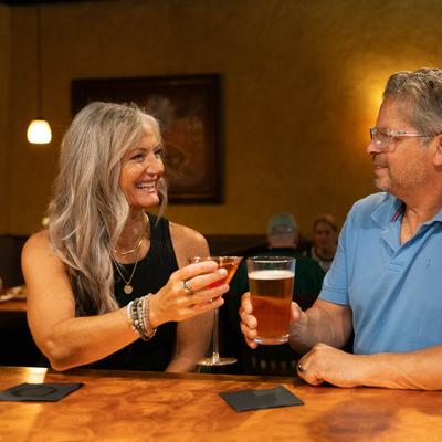 Two people at the bar toasting with drinks.