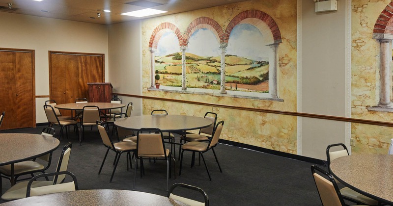 Interior, round tables and seats in a room with mural art on a wall