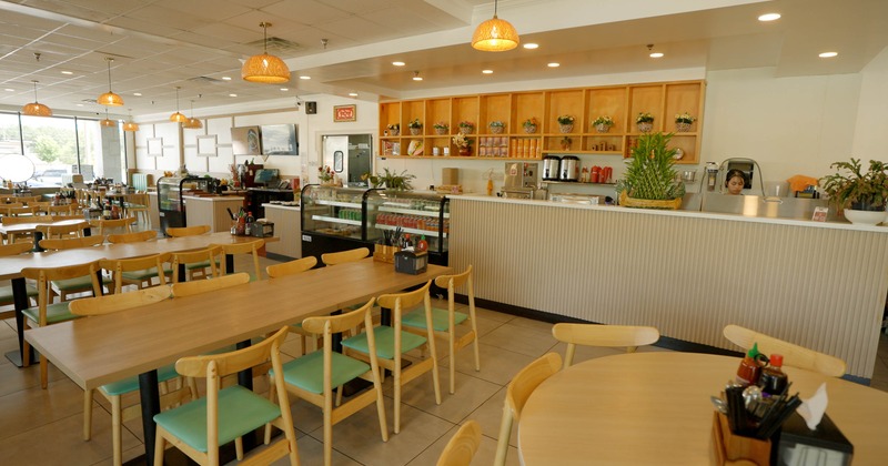 Interior - wooden tables, mint-green chairs, pendant lighting, a counter with decorative plants
