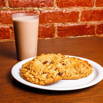 Chocolate chip cookies with a glass of chocolate milk on a wooden table.
