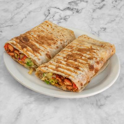 Chicken wrap sliced in half, toasted and served on a white plate.