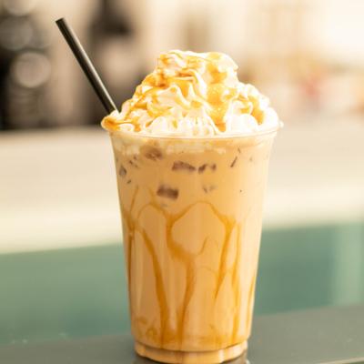 An iced caramel latte in a clear plastic cup with a black straw.